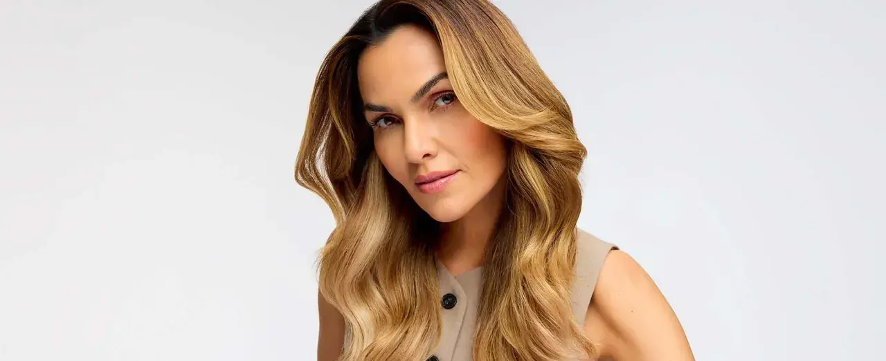 Donna con capelli biondo miele, effetto colpi di sole fai da te, che incorniciano il viso con onde morbide.