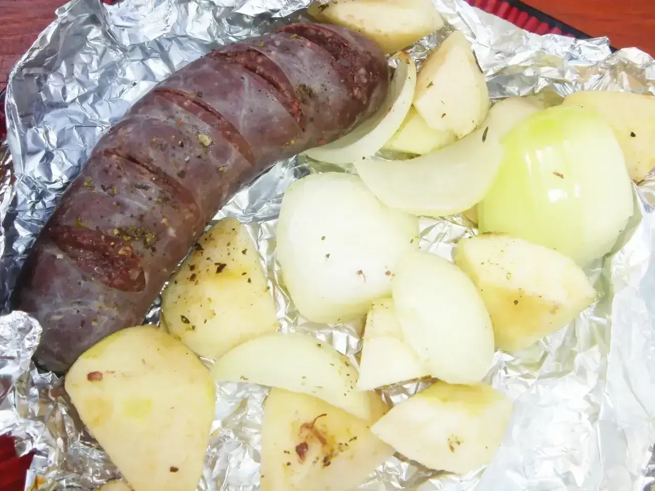 Kaszanka z grilla z cebulą w folii aluminiowej, gotowa do pieczenia. Aromatyczne dodatki podkreślą smak.