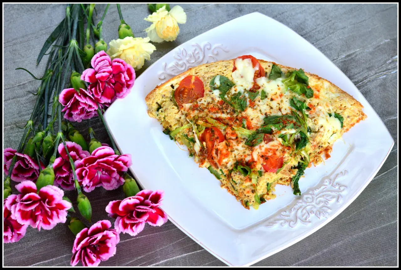 Pyszny omlet z tuńczykiem, pomidorami i zielonymi warzywami, udekorowany kwiatami.