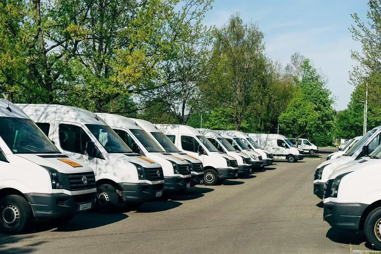 Rząd białych busów do 3,5 tony gotowych do stałych zleceń.