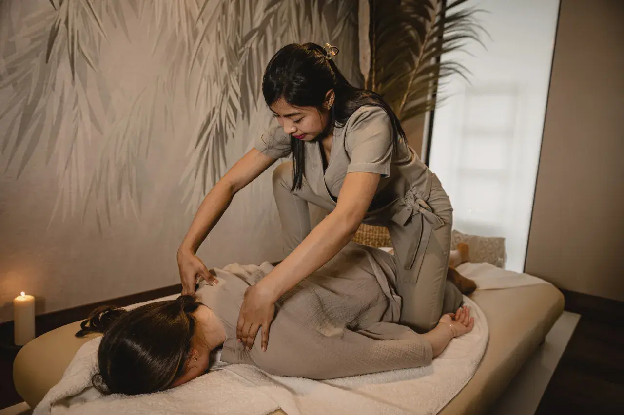 Terapeuta wykonuje masaż shiatsu na osobie leżącej na macie. Relaksująca atmosfera z subtelnym oświetleniem.