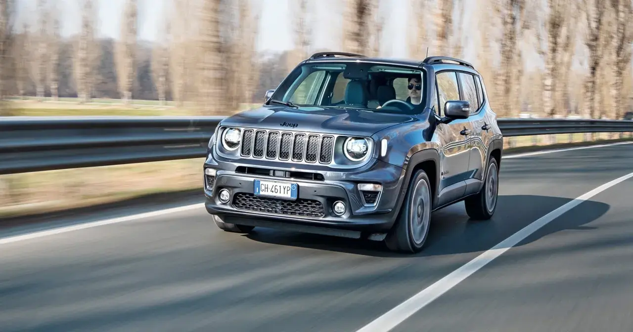 Ciemnoszary Jeep Renegade Hybrid jedzie po drodze, za kierownicą siedzi mężczyzna w okularach.