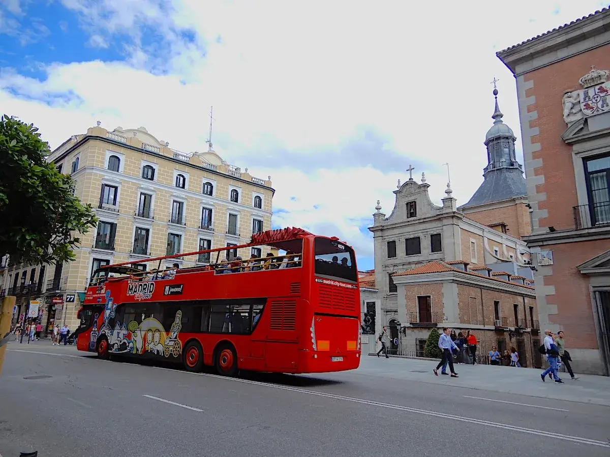 Roter Doppeldeckerbus mit Touristen fährt durch Madrid. Tolle Madrid Tipps für Sightseeing!