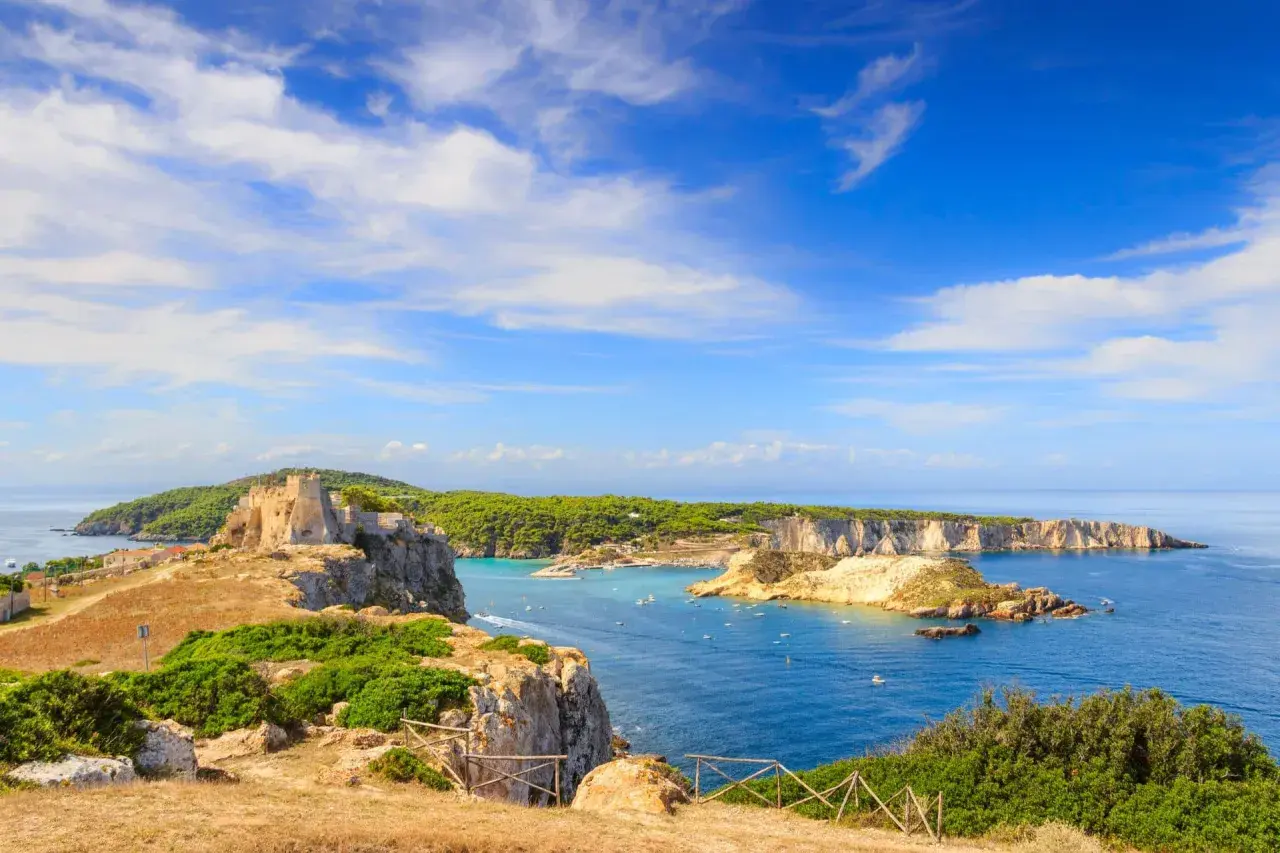 Un antico castello domina le isole della Puglia, con acque azzurre e vegetazione lussureggiante.