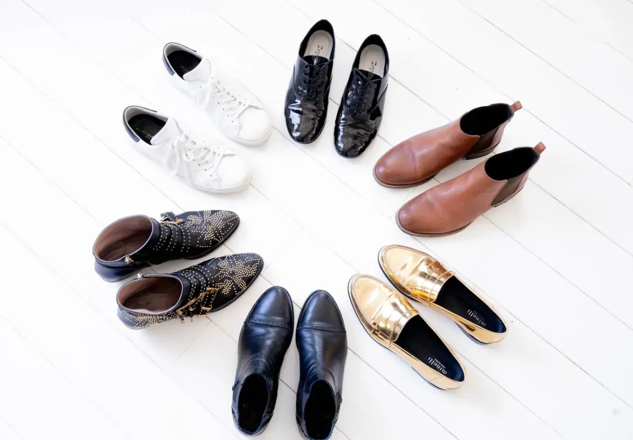 Collection de chaussures variées : baskets blanches, bottines cloutées, mocassins dorés, bottines noires, derbies vernies et bottines marron. Une vraie panoplie de chaussure qui va avec tout !