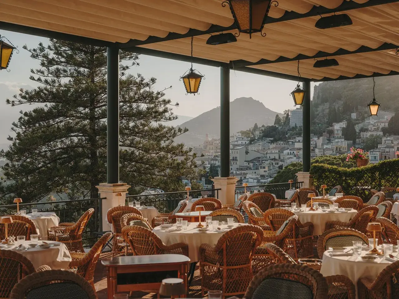 Terrazza con tavoli apparecchiati e vista su Taormina. Un luogo perfetto per un aperitivo al bar Timeo Taormina.
