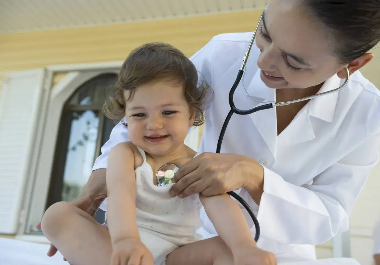 Medico ascolta il cuore di un bambino con uno stetoscopio. Un soffio al cuore cos'è? La visita medica rassicura.