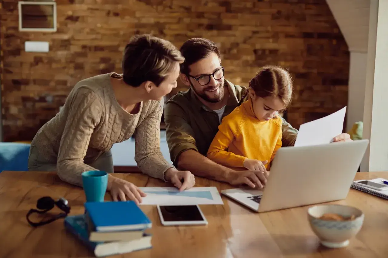 Familj planerar sin ekonomi. Pappa, mamma och dotter vid datorn, diskuterar spartips för hushållsekonomi.