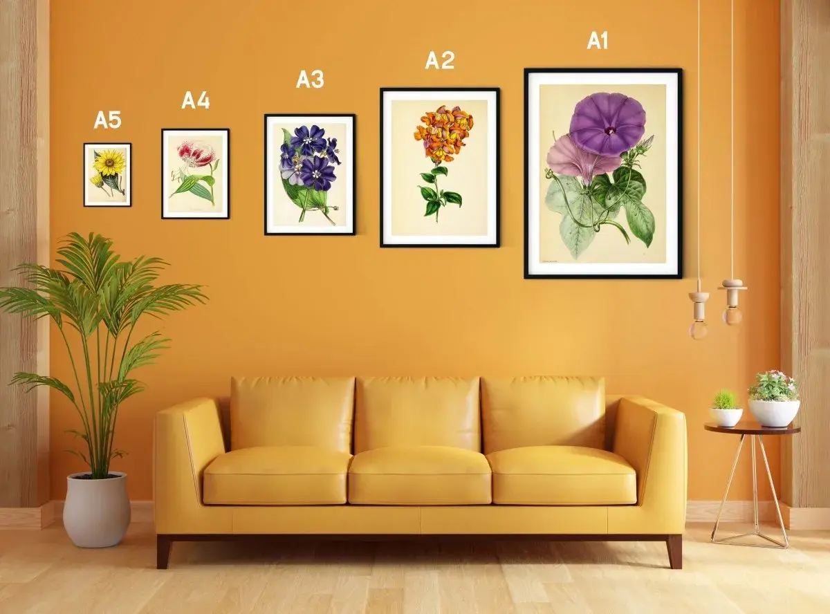 Un sofá amarillo bajo un marco din A3 con flores moradas y rosadas.