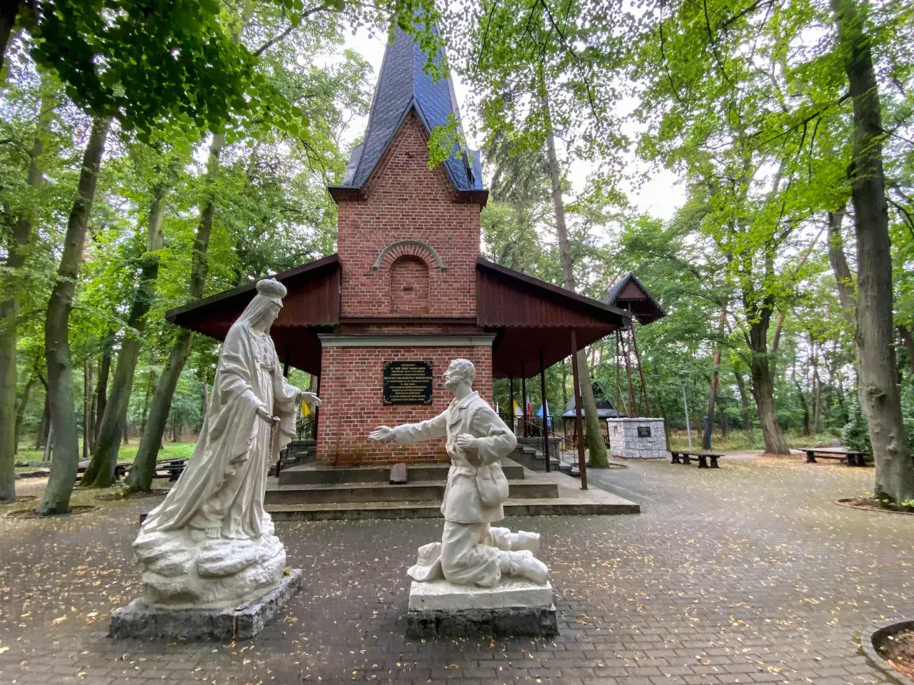 Kapliczka z figurami Matki Bożej i klęczącego mężczyzny. Warto zobaczyć po drodze do Lichenia, piękny las wokół.