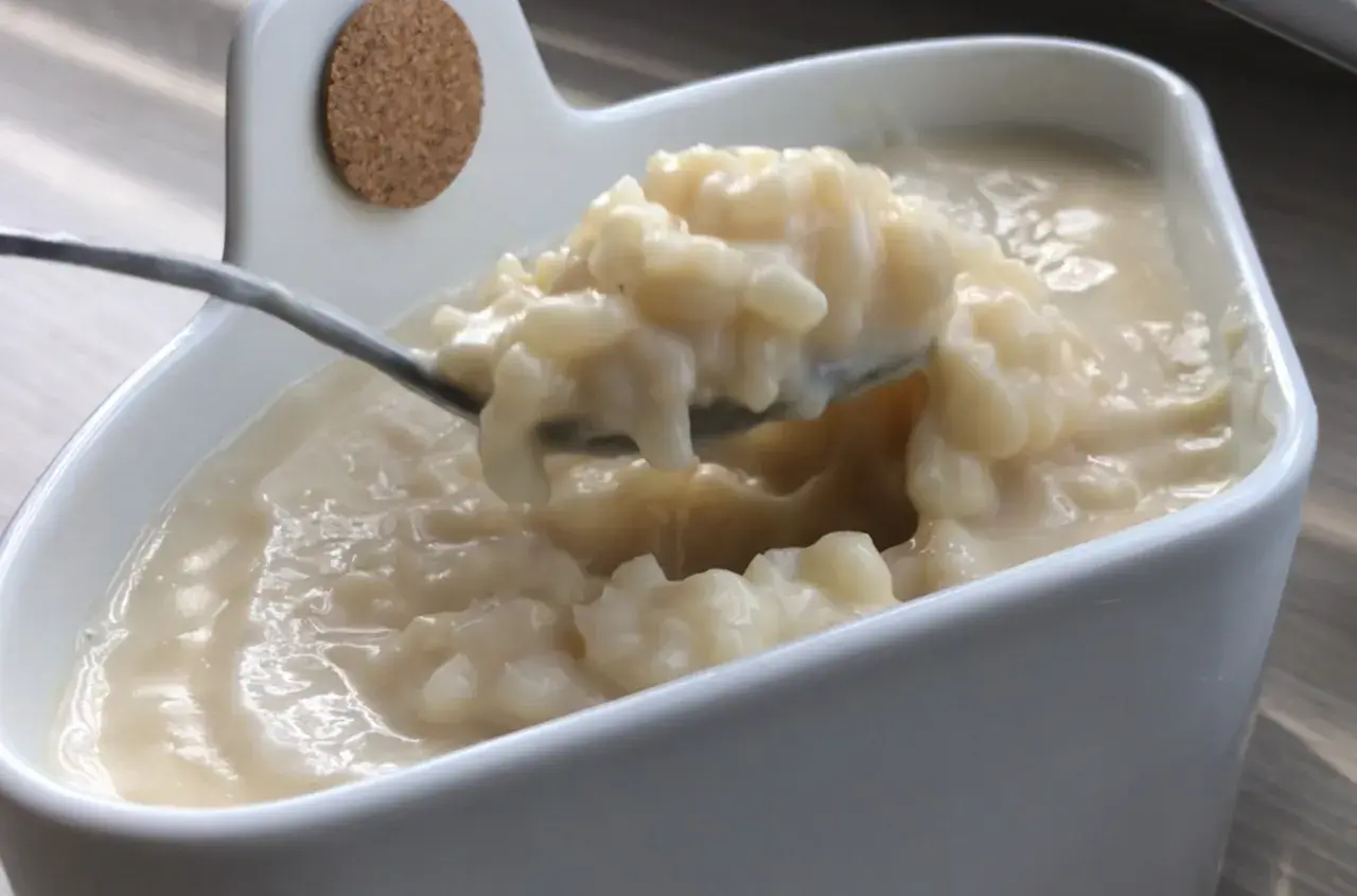 Cuillère prélevant une portion crémeuse de riz au lait dans un bol blanc.