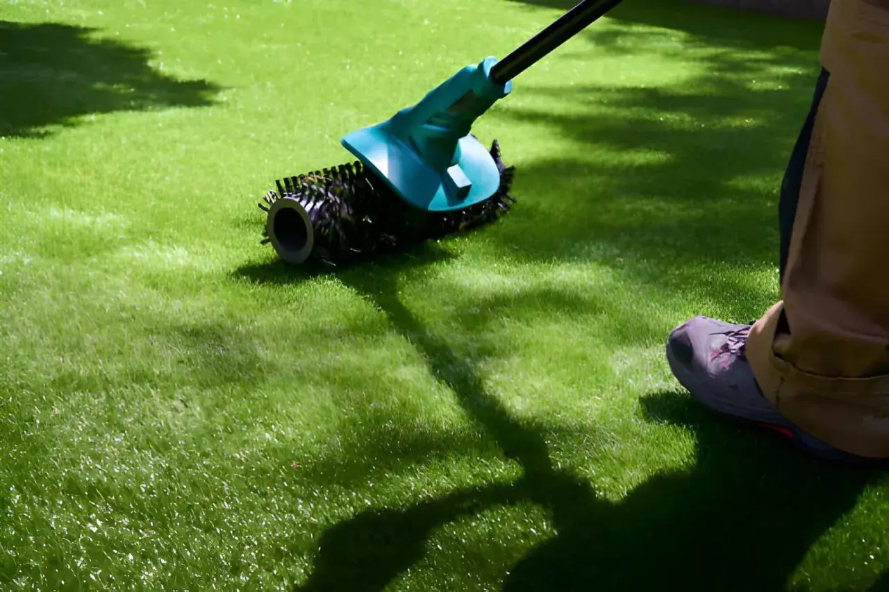 Persona realizando mantenimiento de césped artificial con un cepillo eléctrico.