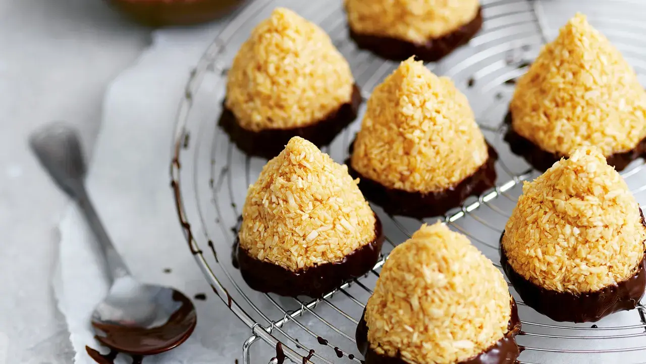 Kokostoppar recept: konfekt med kokos och choklad på ett galler. En sked med choklad ligger bredvid.