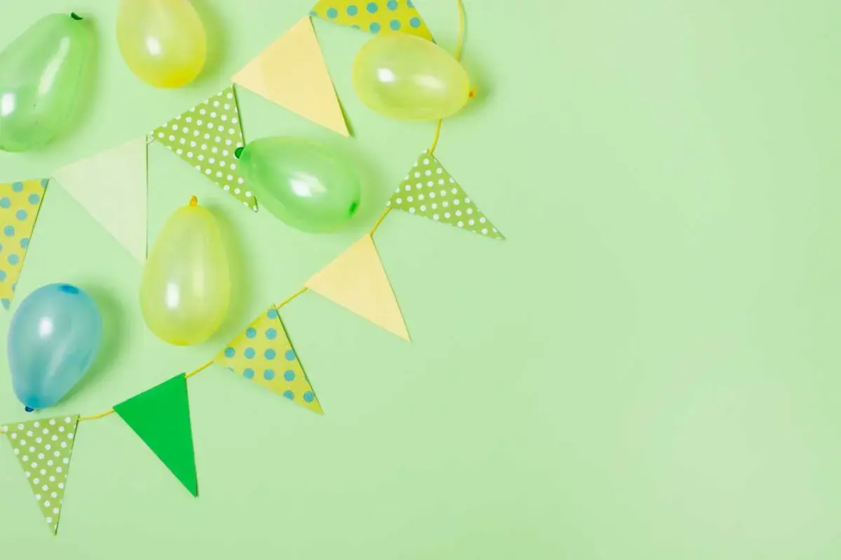 Globos y banderines de colores pastel sobre fondo verde claro, perfectos para ideas de cumpleaños.
