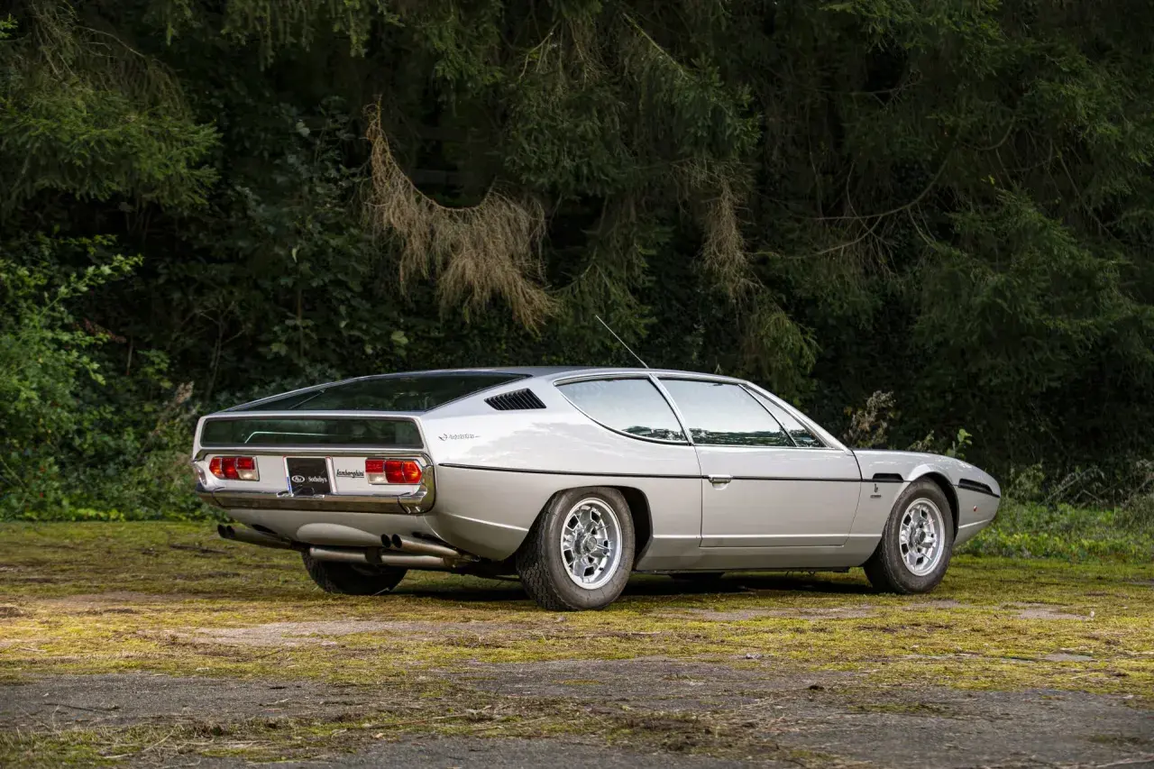 Srebrny Lamborghini Espada z lat 70. na tle zieleni. Klasyk motoryzacji.