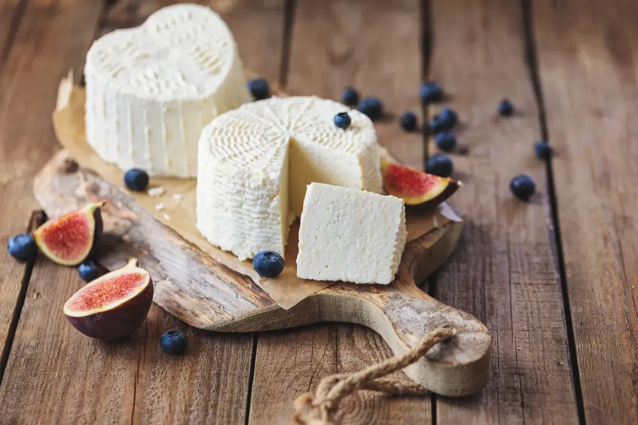 Formaggi freschi su tagliere rustico con fichi e mirtilli. La ricotta, pur essendo un latticino, contiene lattosio.
