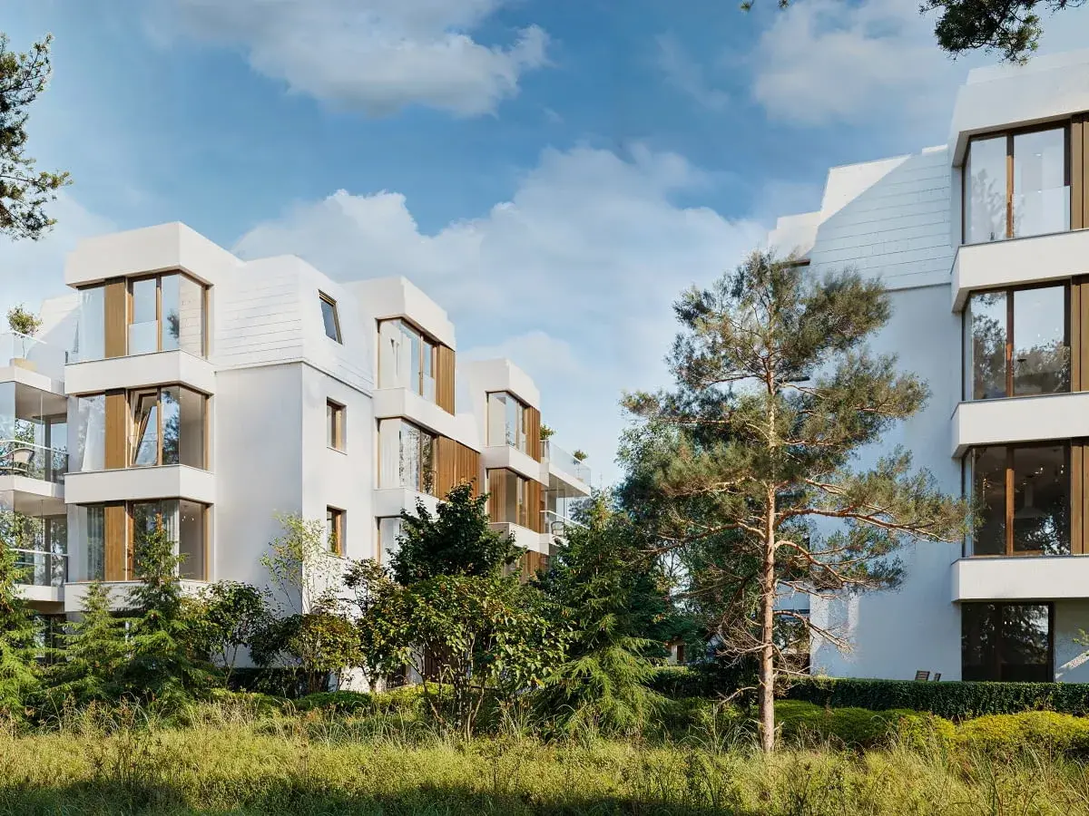 Nowoczesna sopocka architektura, białe budynki z drewnianymi elementami i dużymi oknami, otoczone zielenią.