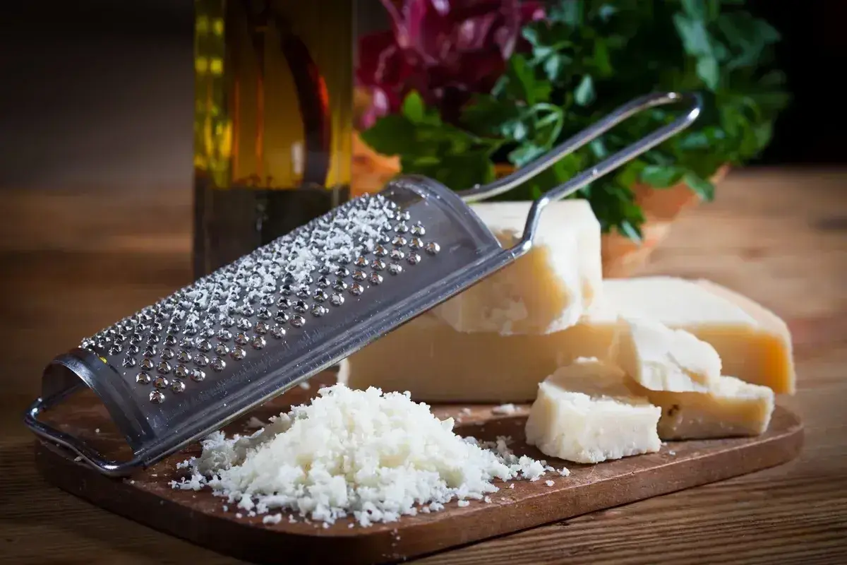 Tarka z grudkami sera, obok kawałki Grana Padano i parmezanu, gotowe do starcia.