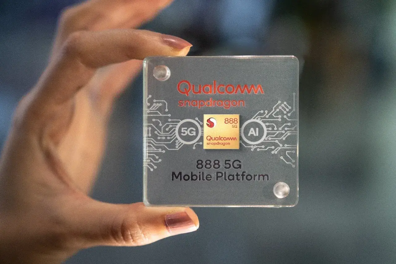 Dłoń trzyma przezroczystą płytkę z logo Qualcomm Snapdragon 888 5G Mobile Platform, symbolizującą moc i innowacje.