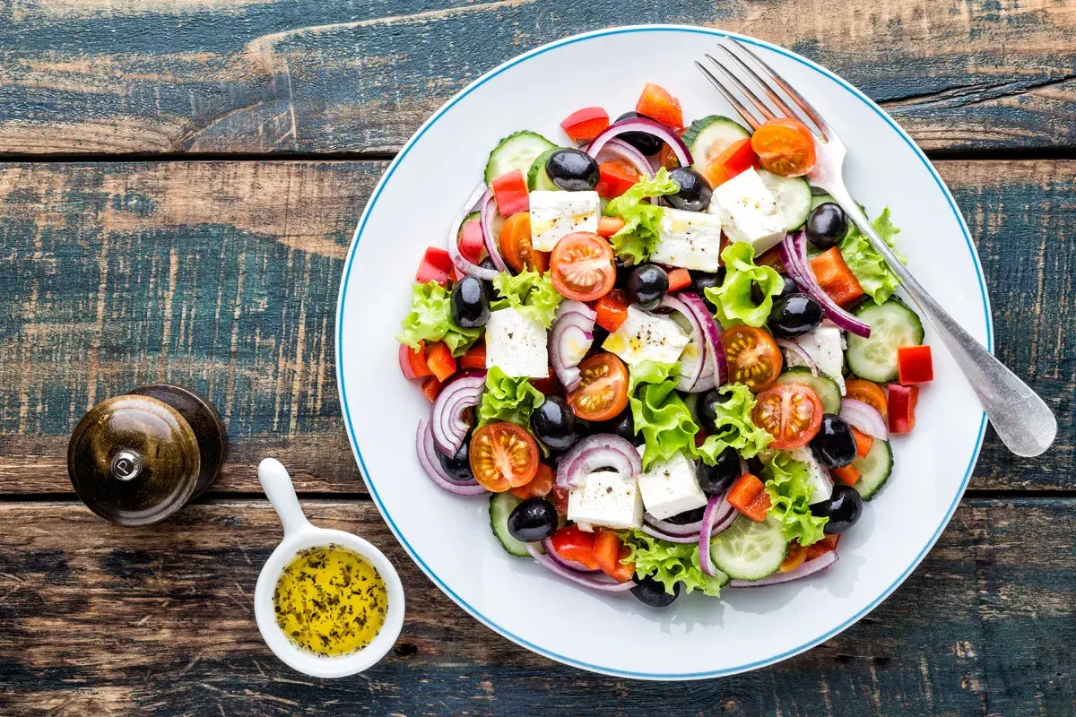 Insalata greca con feta, pomodorini, olive, cetrioli e cipolla rossa. Perfetta per una dieta leggera e gustosa.