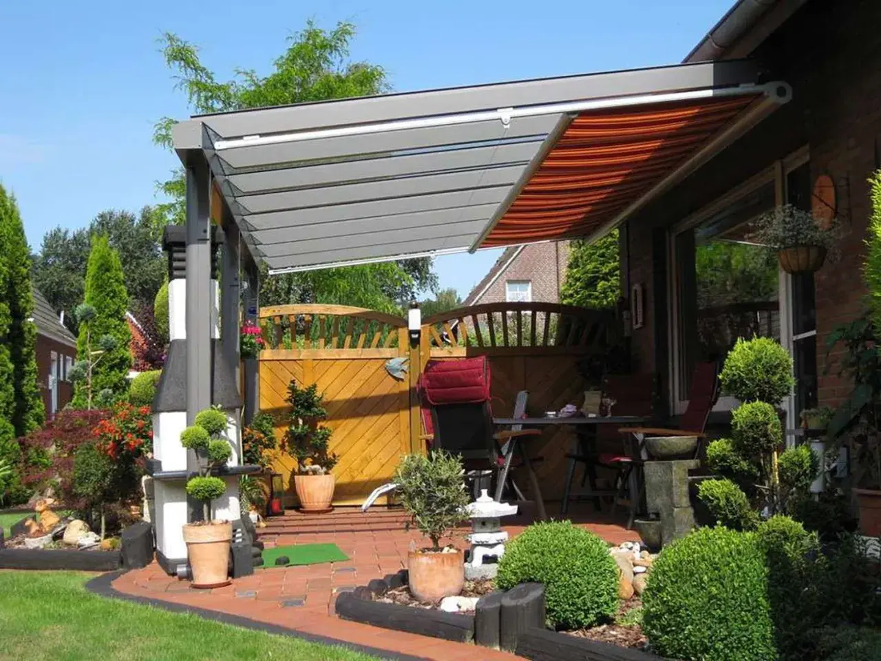 Moderne Terrassenbeschattung Ideen: Eine elegante Pergola mit ausfahrbarem Markisen-Dach schützt die gemütliche Sitzecke im Garten.