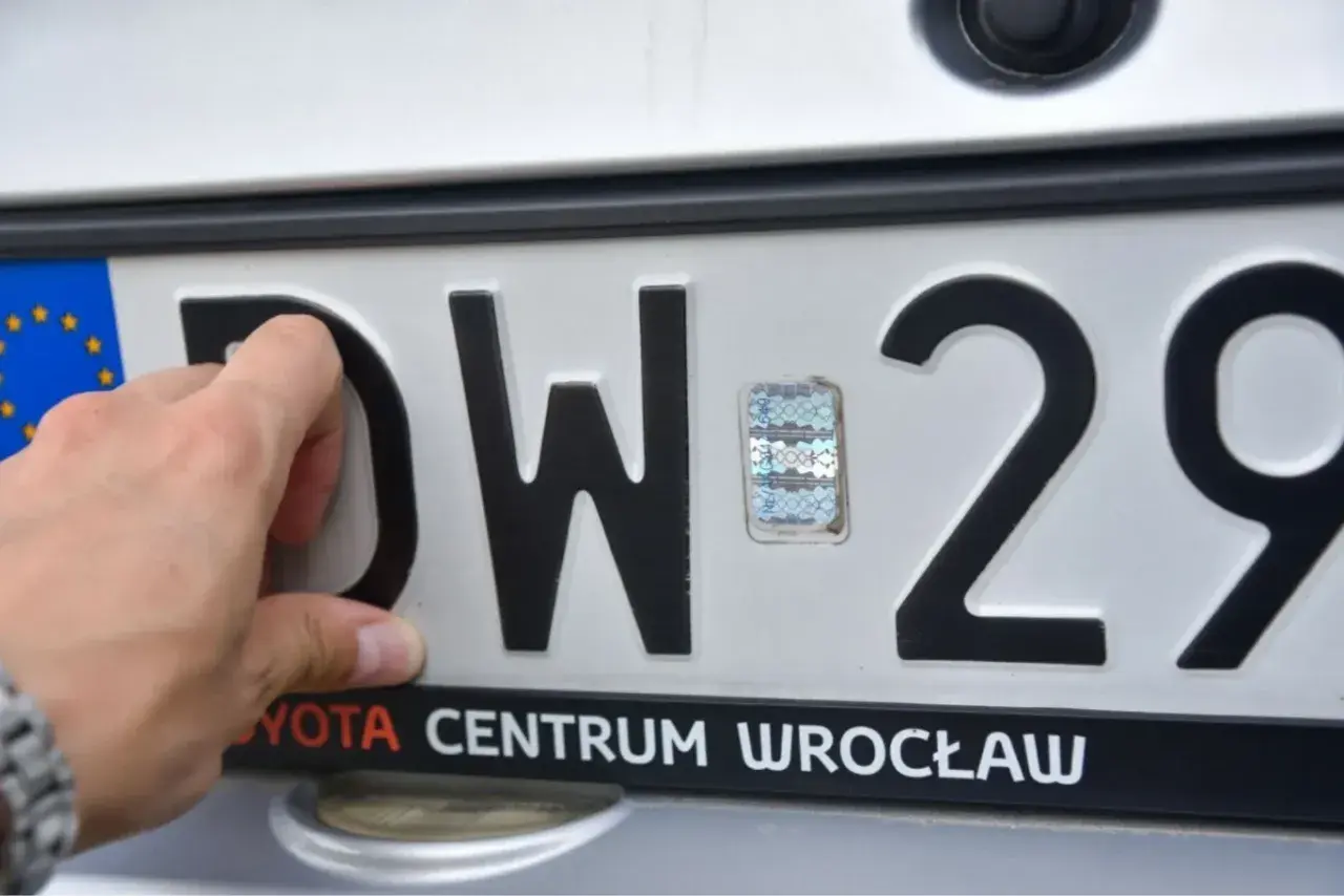 Ręka dotyka litery D na tablicy rejestracyjnej DW 29. Tst rejestracja w Toyota Centrum Wrocław.
