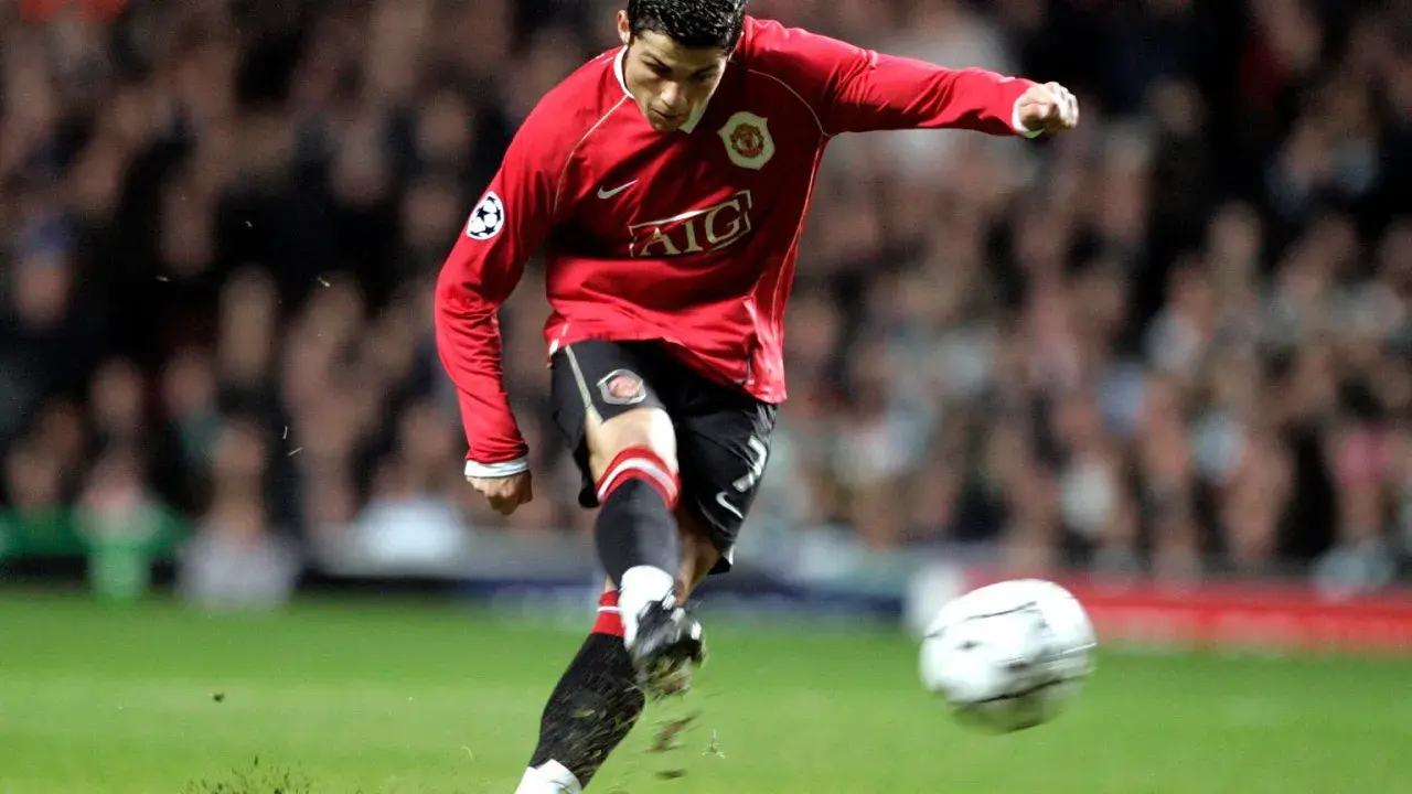 Cristiano Ronaldo w czerwonej koszulce Manchesteru United, z numerem na koszulce, kopie piłkę.