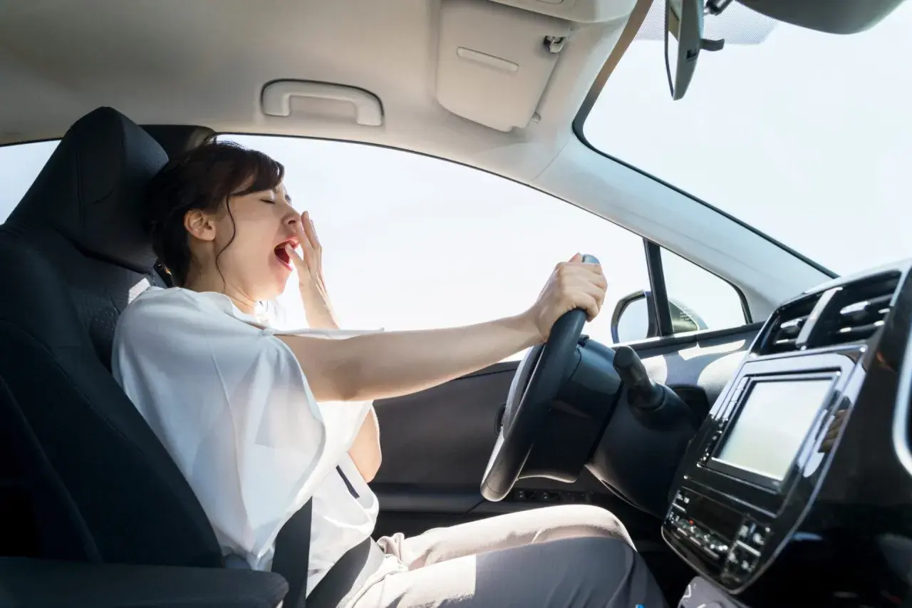 Mujer bostezando al volante. La fatiga puede alterar el tiempo de reacción del conductor, haciendo que el viaje sea peligroso.