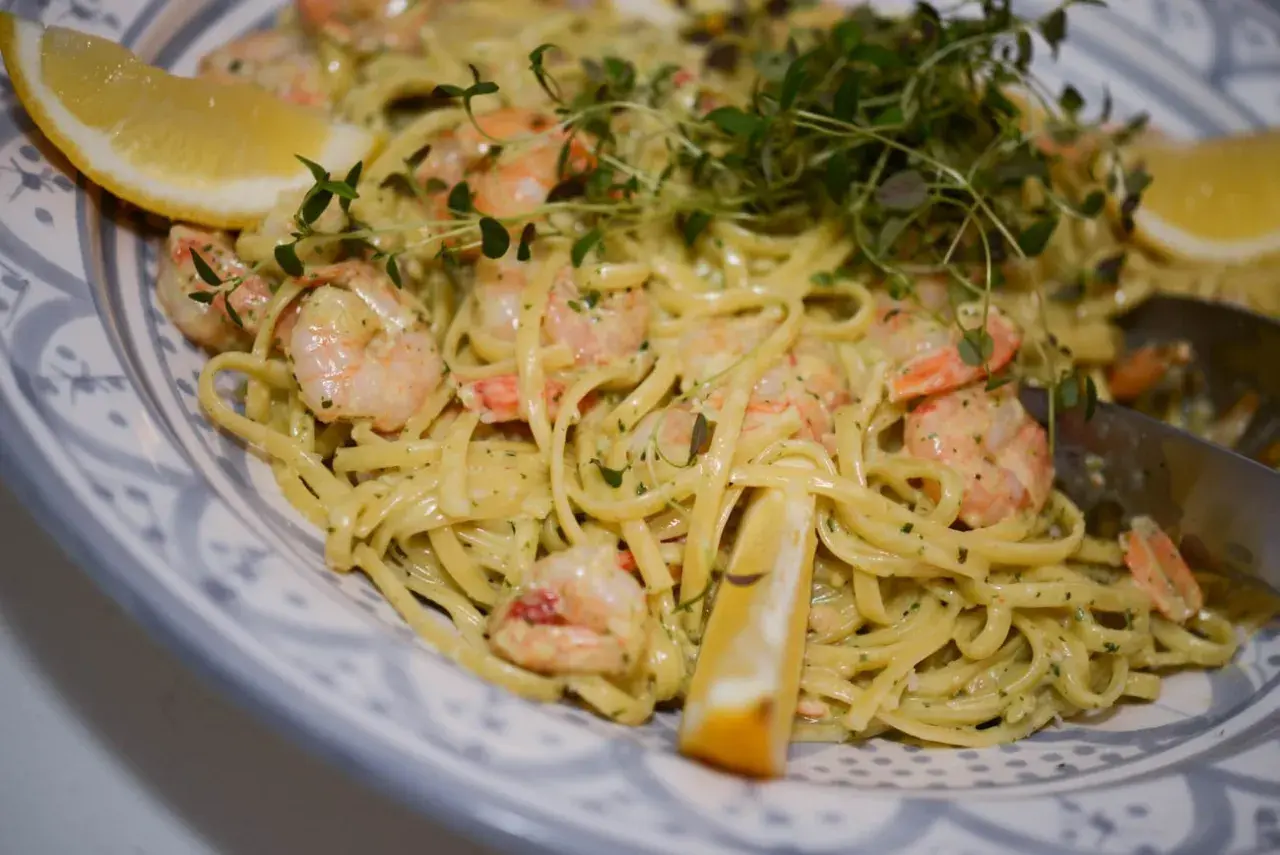 En krämig pasta med scampi och spenat, garnerad med citronklyftor och färska örter. En härlig rätt som passar perfekt för en middag.