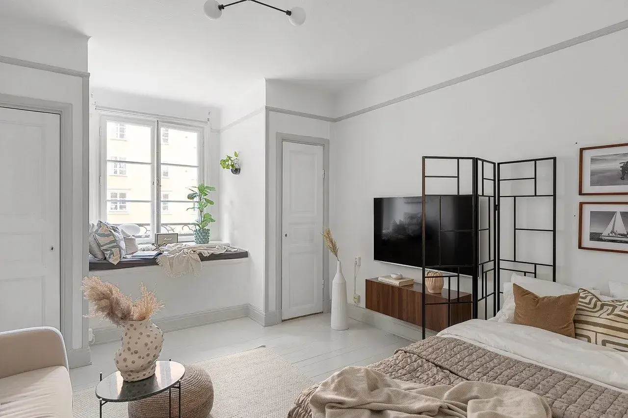 Przytulne mieszkanie bezczynszowe z wygodną kanapą przy oknie, łóżkiem i telewizorem.