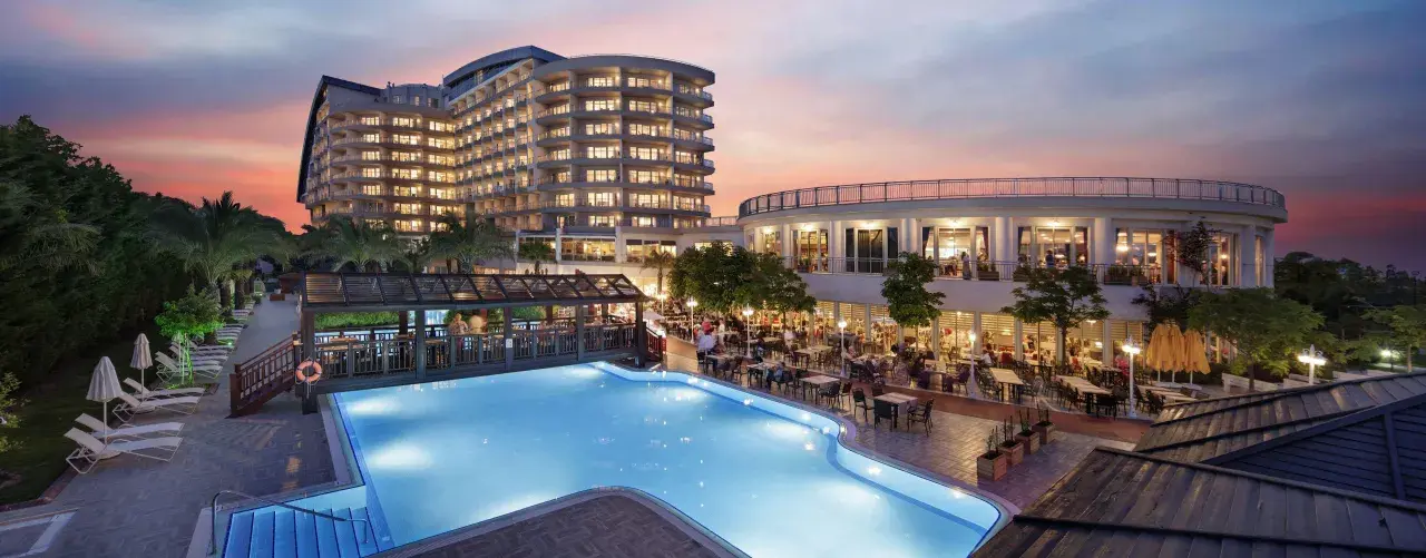 Abendstimmung am Pool des Liberty Lara Hotels. Gäste genießen das Abendessen im Freien unter dem farbenprächtigen Himmel.