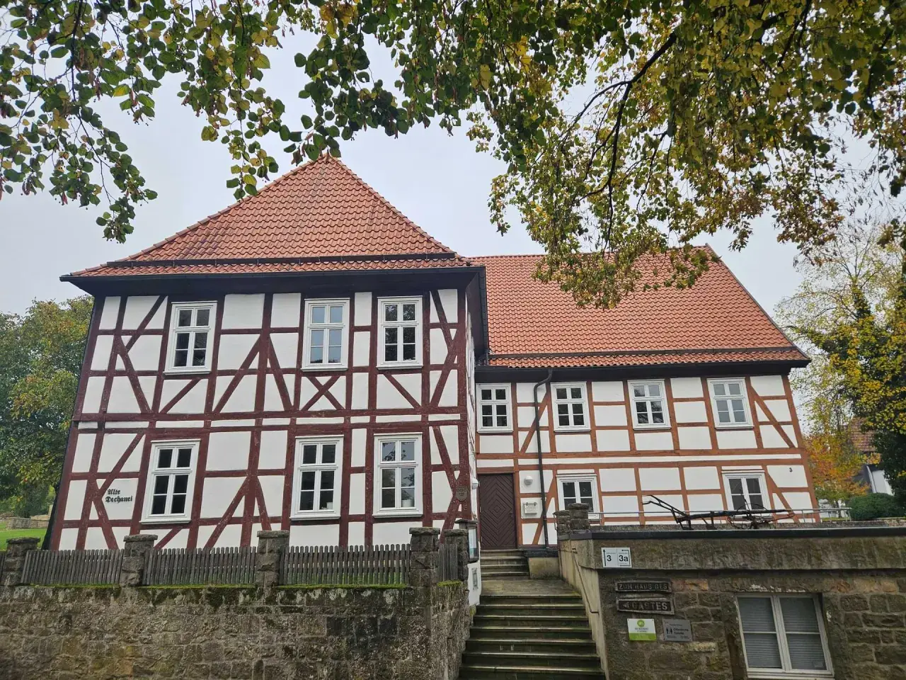 Fachwerkhaus mit roten Ziegeln, das die Wohnung eines Dechanten beherbergt. Ein steinerner Zaun und eine Treppe führen zum Eingang.