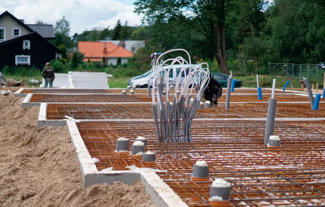 Budowa fundamentów domu: zbrojenie, rury i izolacja.
