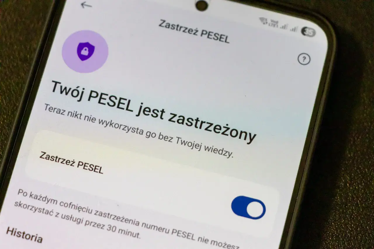 Ekran telefonu z informacją "Twój PESEL jest zastrzeżony" i ikoną tarczy z kłódką.