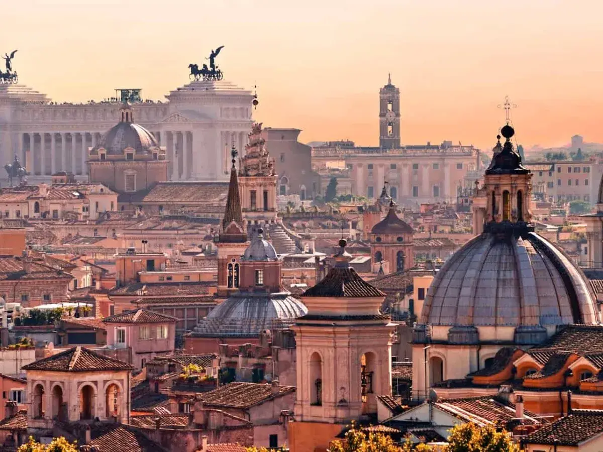 Panorama di Roma al tramonto, con cupole e monumenti iconici. Un invito a scoprire le tante cose da fare a Roma.