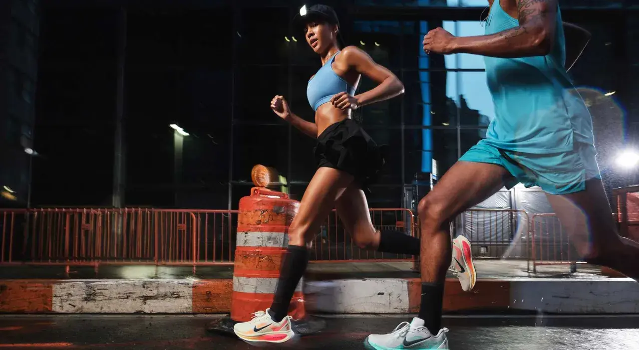 Coppia di runner notturni in città, impegnati in esercizi per migliorare la corsa. Le luci urbane illuminano la loro determinazione.