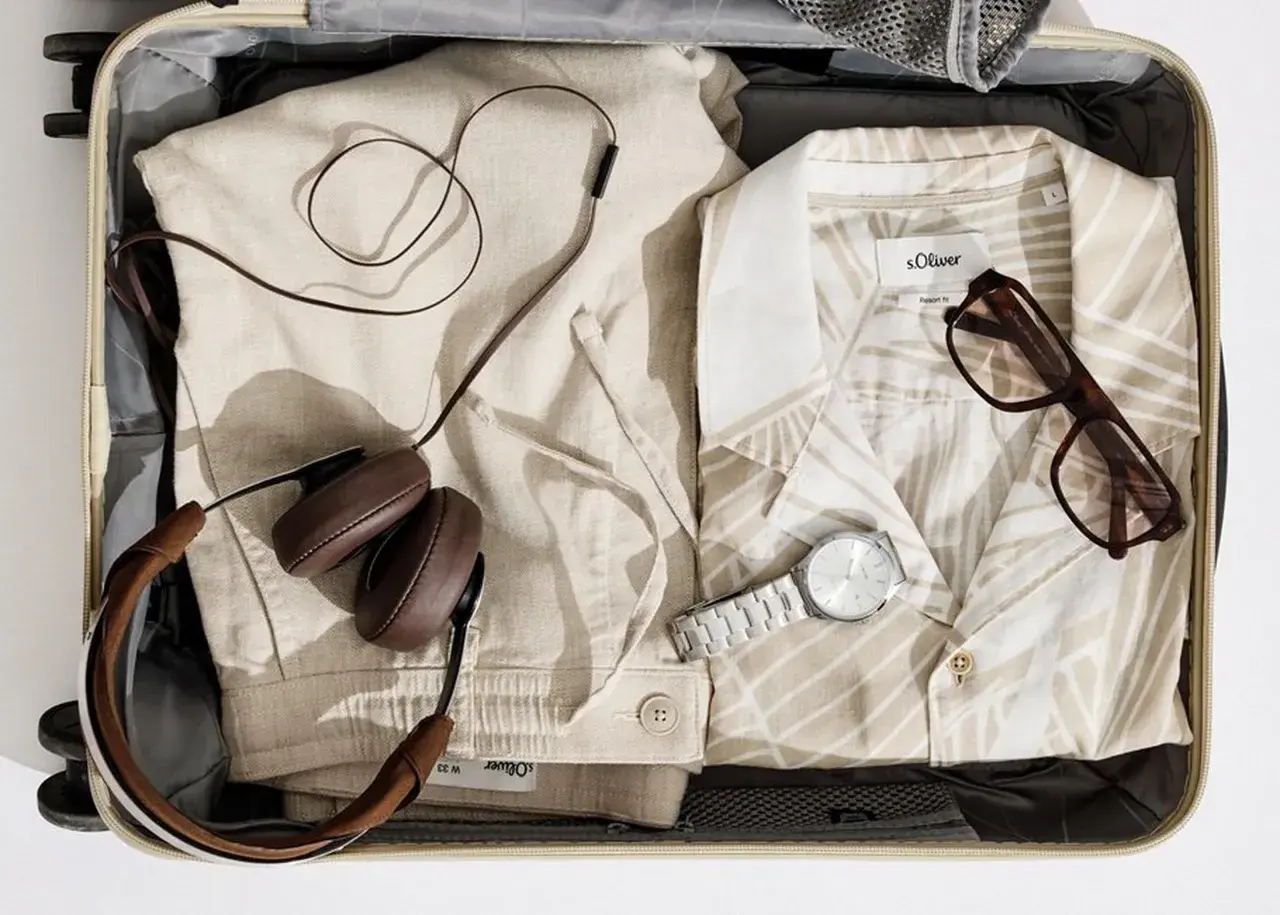 Koffer packen Liste Frauen: Leinenhose, gemustertes Hemd, Kopfhörer, Brille und Uhr für den perfekten Urlaub.
