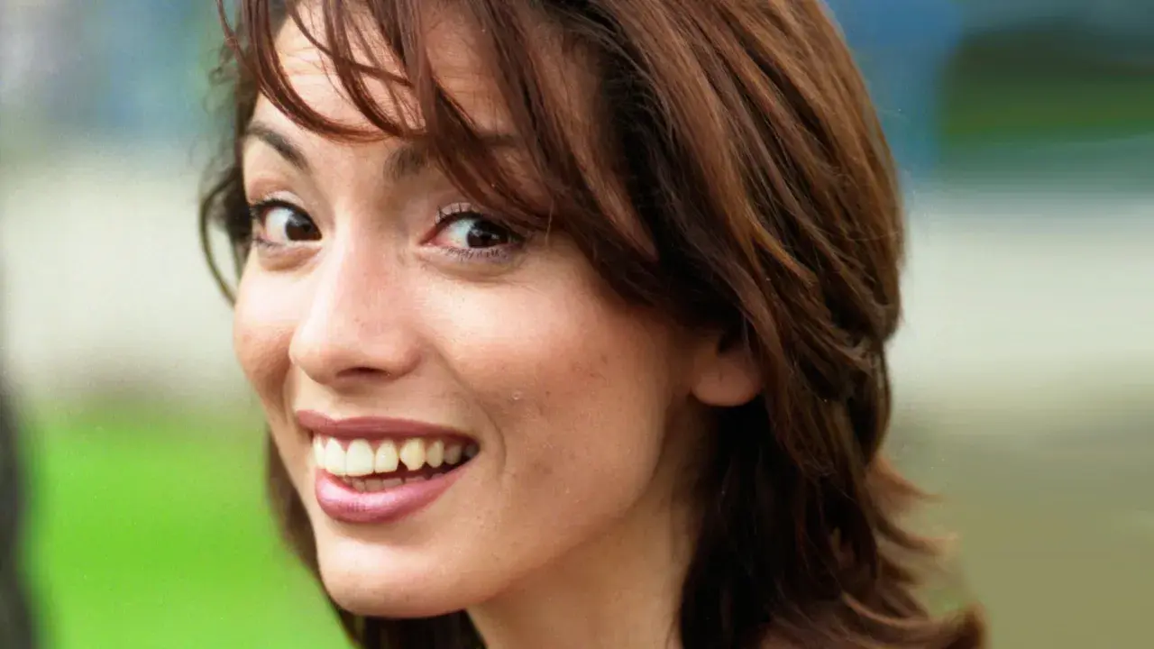 Close-up of a young woman with brown hair, smiling and looking to the side.