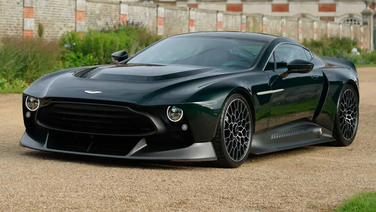 Der Aston Martin Victor, ein dunkelgrüner Supersportwagen, steht auf einem Kiesweg vor einer alten Mauer.
