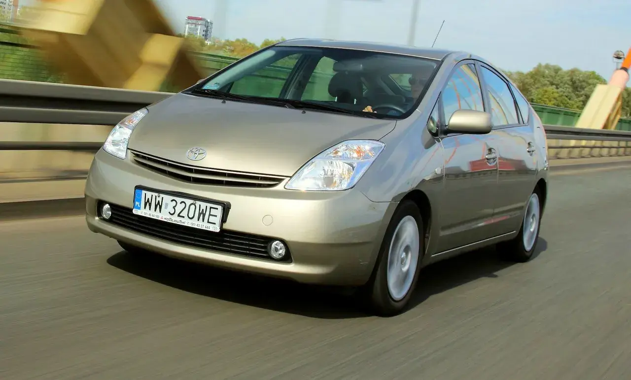 Złoty Toyota Prius 2 jedzie po moście, rejestracja WW 320WE.