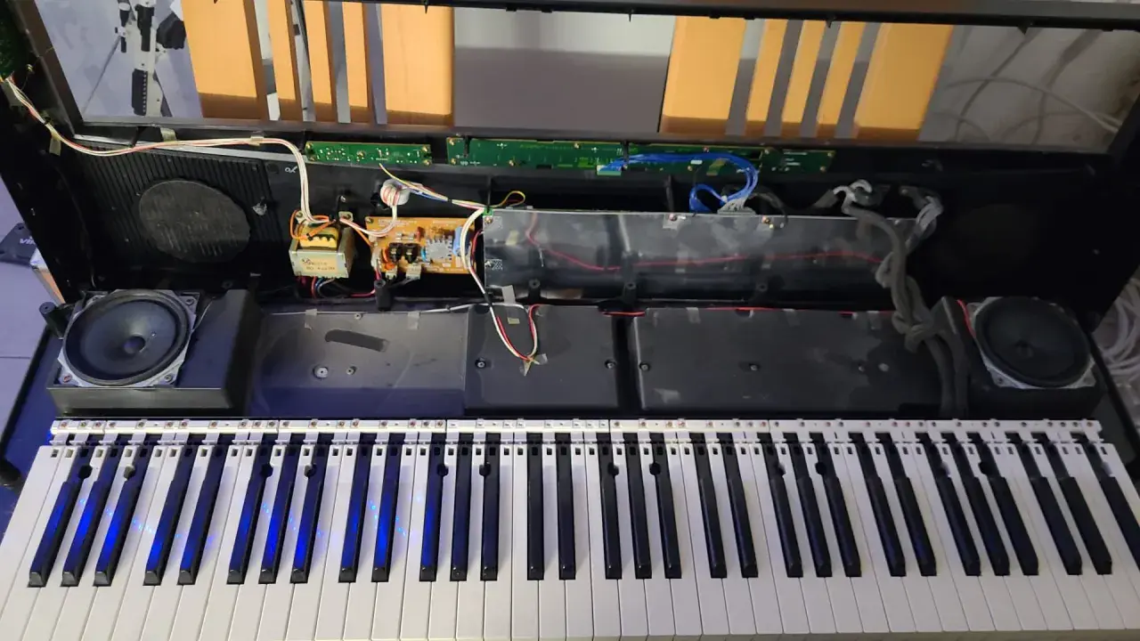 Wnętrze keyboardu podczas naprawy instrumentów muzycznych. Widoczne głośniki, płytki drukowane i okablowanie.