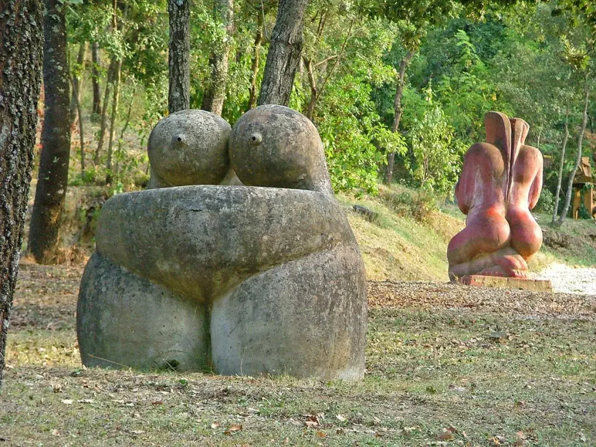 Esculturas de piedra en un museo al aire libre, evocando formas humanas en un entorno natural.