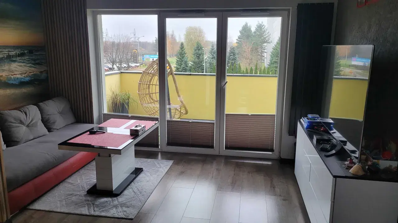 Wygodny salon z widokiem na atrium Radogoszcz. Na tarasie huśtawka i zieleń.