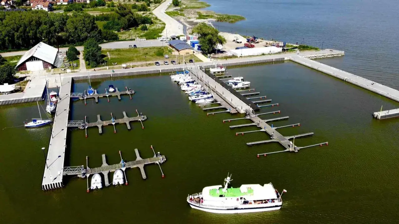 Widok z lotu ptaka na port w Krynicy Morskiej z licznymi łodziami i żaglówkami przy pomostach.