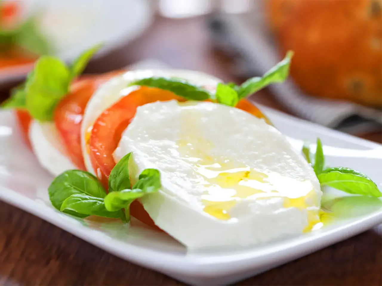 Frische Insalata Caprese mit saftigen Tomaten, cremigem Mozzarella und Basilikum, beträufelt mit Olivenöl. Ein Genuss!
