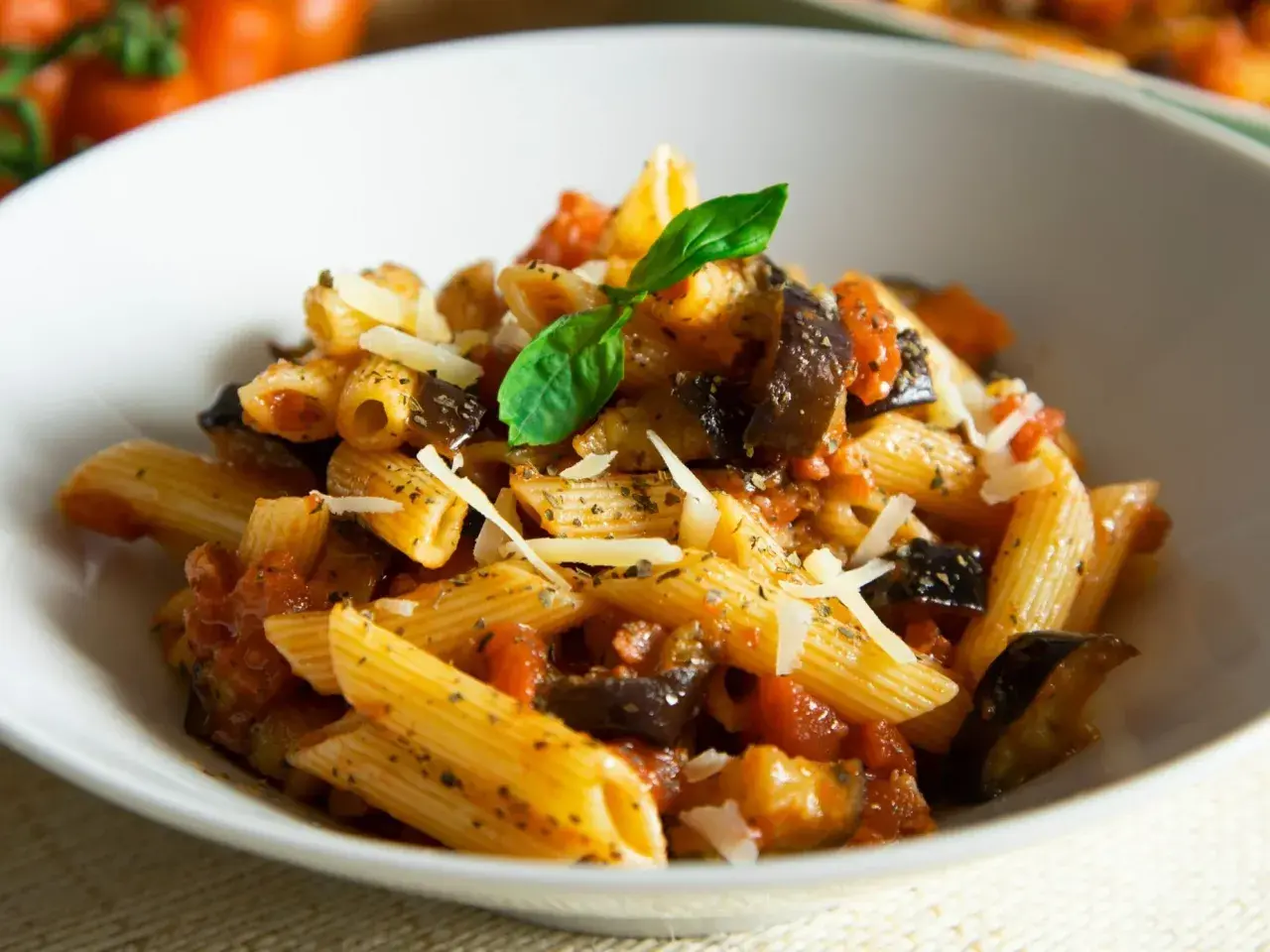 Penne z bakłażanem i pomidorami, posypane parmezanem. Proste danie włoskie, które zachwyca smakiem.