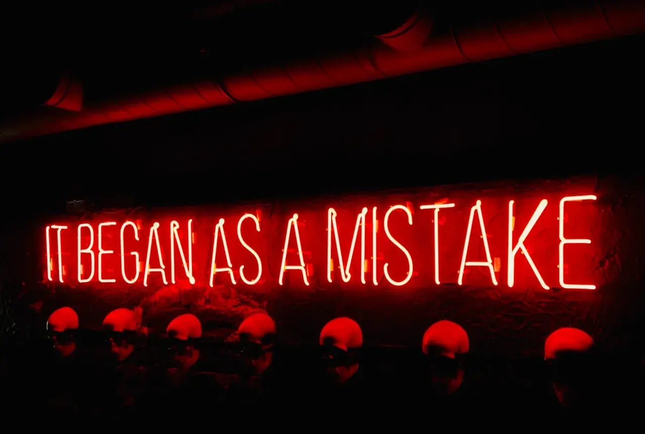 Neon rosso "IT BEGAN AS A MISTAKE" sopra teschi. Come si dice "lunedì" in inglese? Monday.