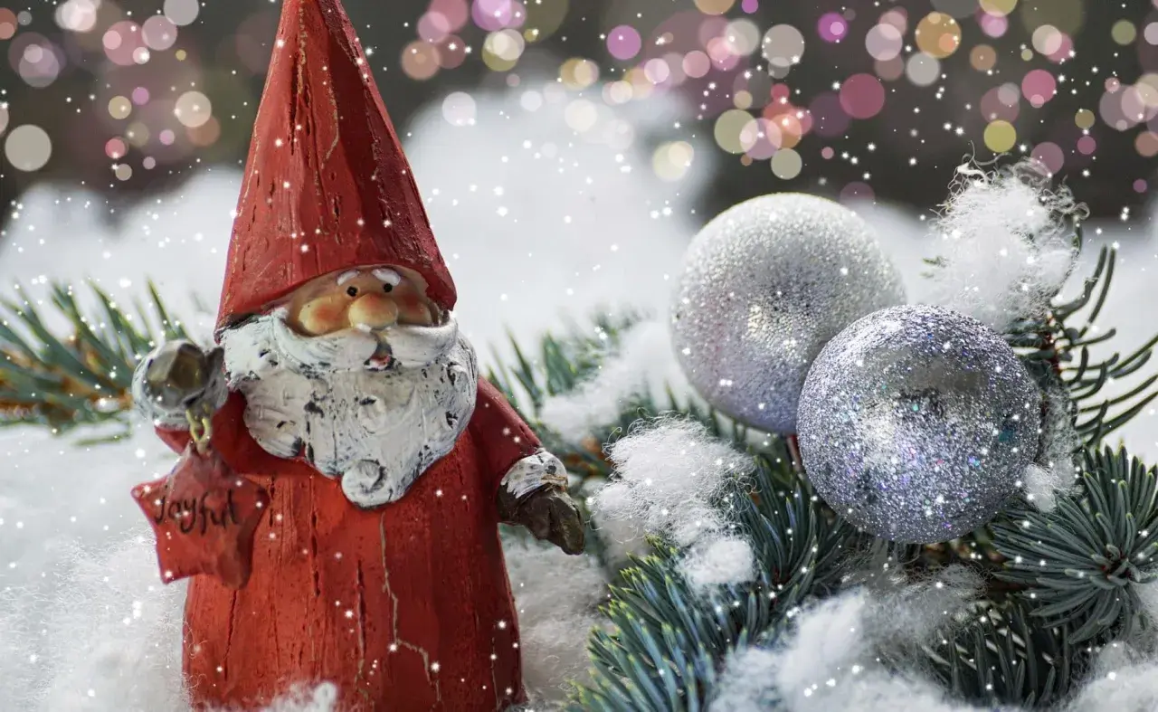 Weihnachtsdeko tipps: Ein Weihnachtsmann mit Stern und Glitzerkugeln auf Tannenzweigen im Schnee.