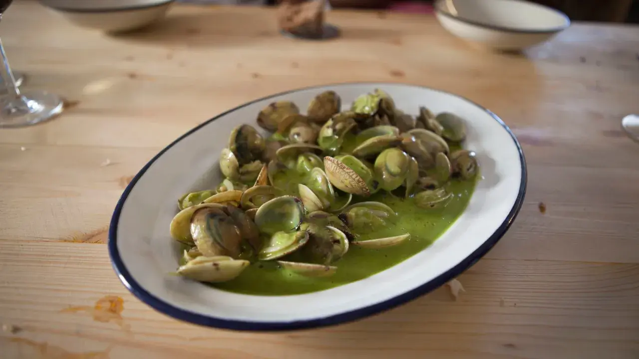 Plato de almejas en salsa verde, un manjar marino bañado en una vibrante y sabrosa salsa.