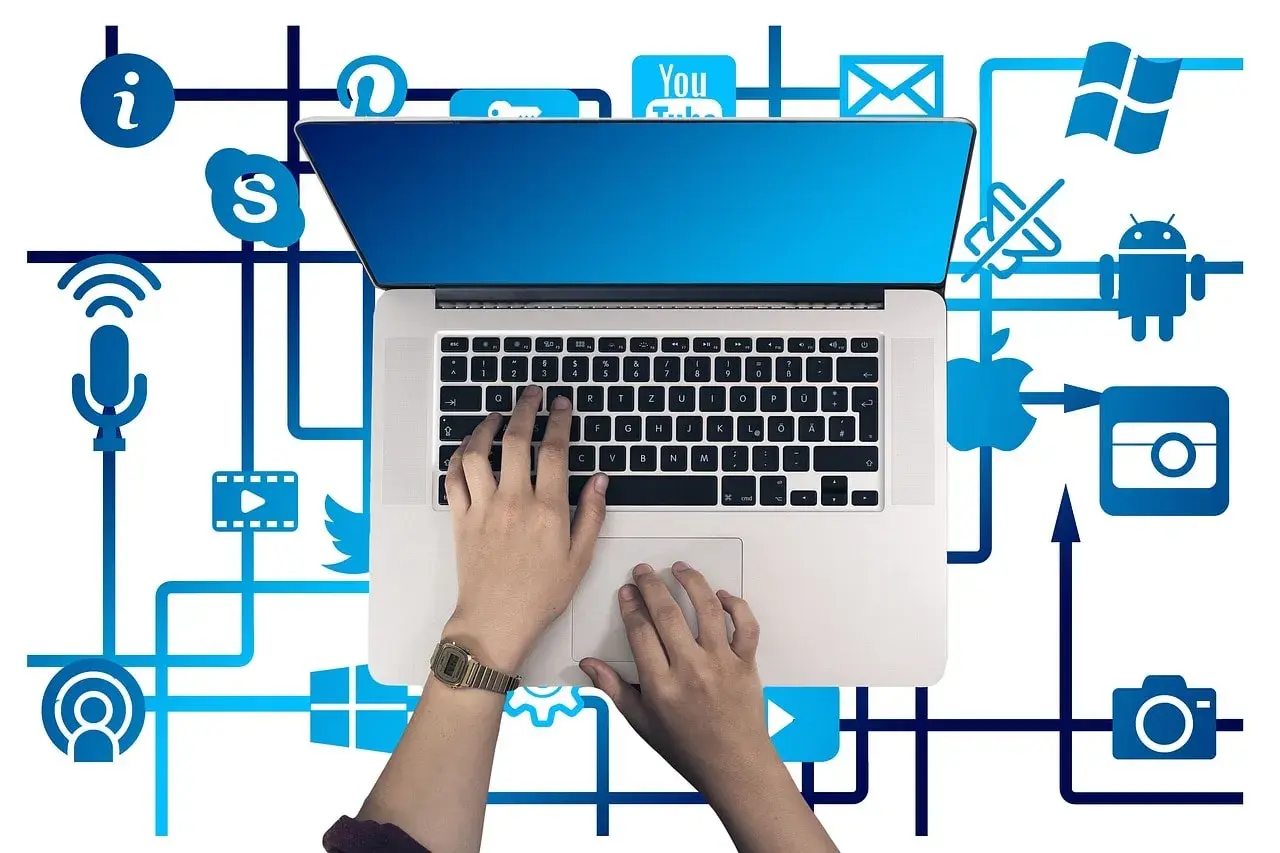 Ręce na klawiaturze laptopa, otoczone ikonami mediów społecznościowych i usług, tworzą sieć połączeń, symbolizującą pętlę przekierowań w cyfrowym świecie.